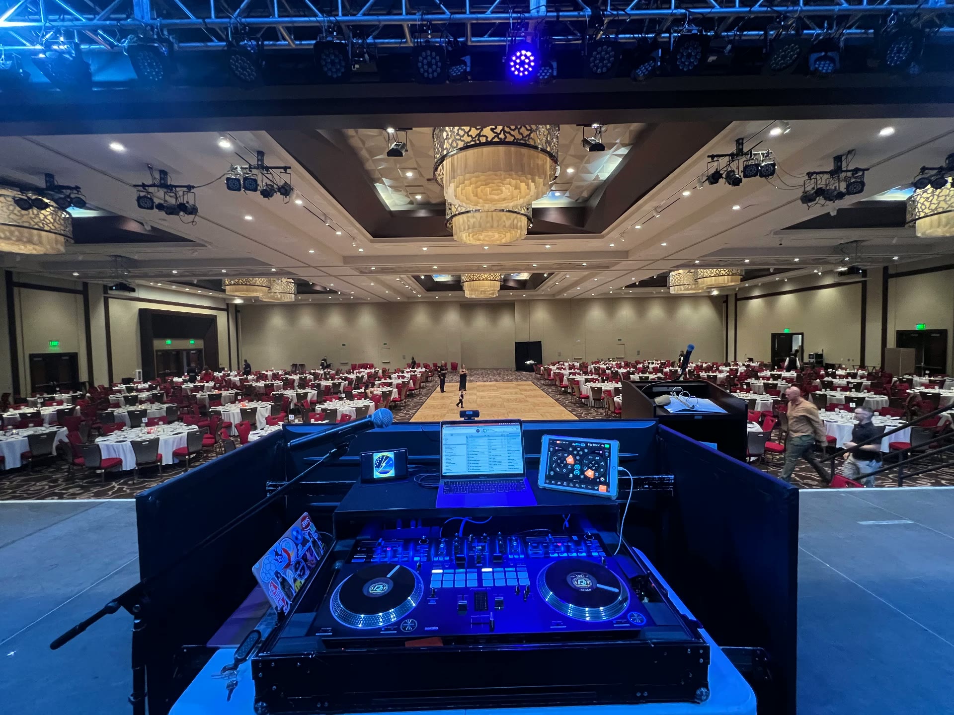 DJ booth overlooking a grand ballroom with chandeliers and dance floor