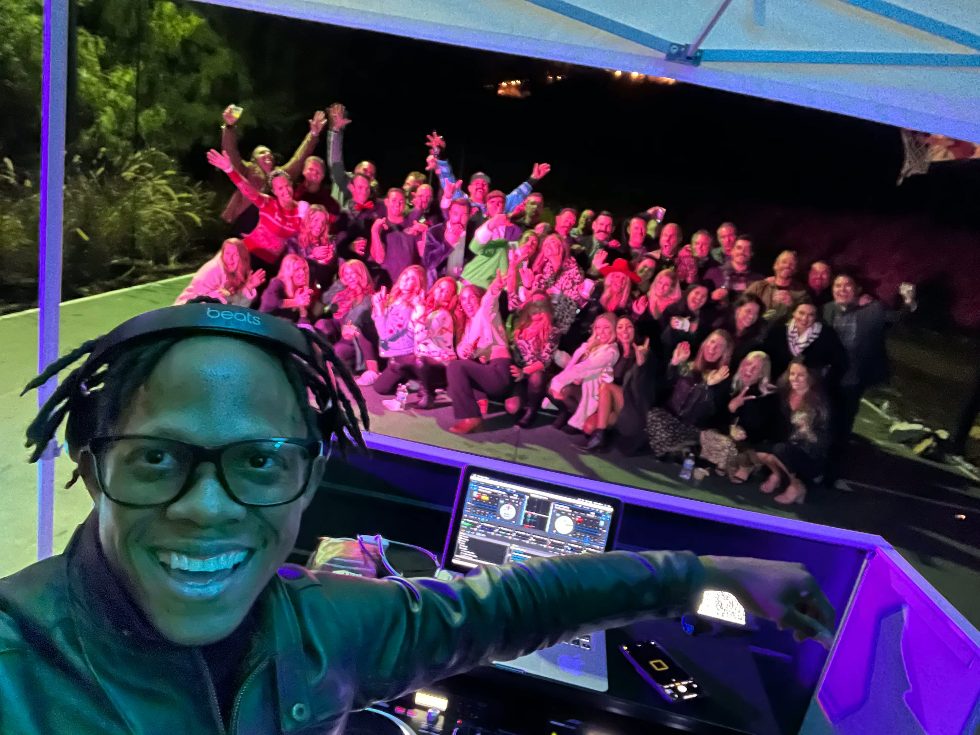 DJ Suppa Millz smiling at the booth in front of a cheering costumed crowd